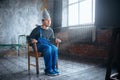 Afraided man in aluminum foil helmet sits in chair Royalty Free Stock Photo