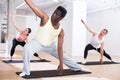Aframerican man doing pilates workout with group at gym