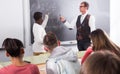 Aframerican student answers near blackboard at math lesson