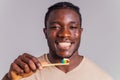 afrian american man holding colorful rainbow toothbrush in gray backgroung Royalty Free Stock Photo