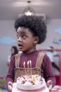 Africa American boy hold on celebrating him birthday cake and blow candles on cake in Kids birthday celebratiion party