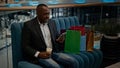 African adult man middle-aged businessman with shopping bags in mall store shop with coffee tea cup browsing scrolling Royalty Free Stock Photo