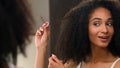 African America woman correct twist curl girl looking mirror reflection touching curly hair enjoy healthy haircare touch Royalty Free Stock Photo