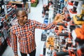 African americam man buying modern electric drill while standing in tool. Hardware construction site objects concept Royalty Free Stock Photo