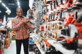 African americam man buying modern electric drill while standing in tool. Hardware construction site objects concept Royalty Free Stock Photo