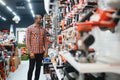 African americam man buying modern electric drill while standing in tool. Hardware construction site objects concept Royalty Free Stock Photo