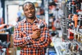 African americam man buying modern electric drill while standing in tool. Hardware construction site objects concept Royalty Free Stock Photo