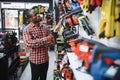 African americam man buying modern electric drill while standing in tool. Hardware construction site objects concept Royalty Free Stock Photo