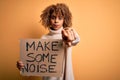 African american activist woman asking for revolution holding banner with make noise message pointing with finger to the camera Royalty Free Stock Photo