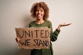 African american activist woman asking for unity holding banner with united stand message very happy and excited, winner