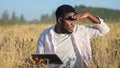 African American agronomist explores ripe wheat plantation at sunset light.