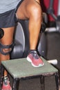 African american athlete with knee brace perfroming step ups on plyo box with dumbells