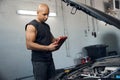 African American auto-mechanic using tablet to check electronic system of car Royalty Free Stock Photo