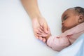 African American baby newborn is 3 months old, sleeping on white bed and mother holding her hand with love Royalty Free Stock Photo