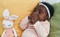 African american baby sitting on bed sucking hand at bedroom Royalty Free Stock Photo