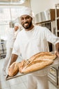 african american baker taking bread loaves from oven Royalty Free Stock Photo