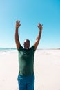 African american bald senior man with arms raised meditating on sandy beach under clear sky Royalty Free Stock Photo