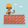 Young african bricklayer building a brick wall.