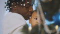 African american black father holding adorable mulatto baby near the christmas tree. Baby yawning