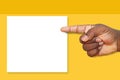 African, Black Man`s Hand Pointing at a Blank Sign on a Mustard Yellow Background Royalty Free Stock Photo