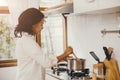 African American Black woman cooking boiling soup in the kitchen at home Royalty Free Stock Photo