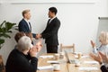 Black ceo and white businessman shaking hands at group meeting Royalty Free Stock Photo