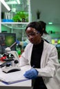 African american botanist researcher writing biological experiment results on clipboard