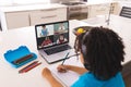 African american boy with curly hair writing notes while learning from online class over laptop Royalty Free Stock Photo