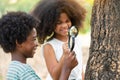 African American boy with friends exploring and looking bugs on the tree with the magnifying glass between learn beyond the Royalty Free Stock Photo