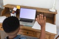 African american boy having video call using laptop during class, raising hand at home Royalty Free Stock Photo