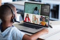 African american boy in headphones and looking at teacher and students during online class on laptop Royalty Free Stock Photo