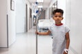 African american boy patient walking with drip stand in hospital corridor with copy space Royalty Free Stock Photo