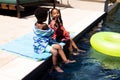 African american boy sharing his ice cream with sister while sitting at poolside at resort in summer