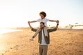 African american boy sitting on father's shoulders family walking on beach by seaside, spending evening together Royalty Free Stock Photo