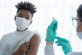 African American boy wear mask looking at Caucasian woman doctor wear gloves using syringe to suck vaccine out of vial