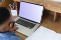 African american boy wearing face mask, having video call lesson using laptop during class at home Royalty Free Stock Photo