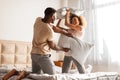 African American boyfriend and girlfriend having fun pillow fight indoor Royalty Free Stock Photo