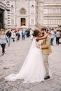 Interracial wedding couple. Wedding in Florence, Italy. African-American bride and Caucasian groom cuddling in Piazza