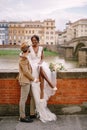 Interracial wedding couple. Wedding in Florence, Italy. An African-American bride is sitting on a brick wall and