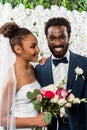 African american bride in white veil smiling near bridegroom and flowers Royalty Free Stock Photo