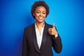 African american business executive woman over isolated blue background doing happy thumbs up gesture with hand Royalty Free Stock Photo