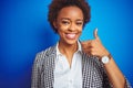 African american business executive woman over isolated blue background doing happy thumbs up gesture with hand Royalty Free Stock Photo