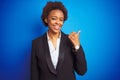 African american business executive woman over isolated blue background smiling with happy face looking and pointing to the side Royalty Free Stock Photo