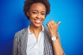 African american business executive woman over isolated blue background smiling with happy face looking and pointing to the side Royalty Free Stock Photo