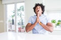 African American business man begging and praying with hands together with hope expression on face very emotional and worried