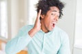 African American business man wearing elegant shirt smiling with hand over ear listening an hearing to rumor or gossip Royalty Free Stock Photo