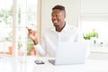 African american business man working using laptop with a big smile on face, pointing with hand and finger to the side looking at Royalty Free Stock Photo