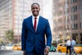 African american business professional in a suit and tie, smiling while walking to workplace office in financial district, city ba Royalty Free Stock Photo