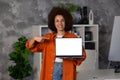 African American business woman holding laptop with blank screen stands in a modern office looking at the camera and smiling Royalty Free Stock Photo