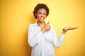 African american business woman over isolated yellow background Showing palm hand and doing ok gesture with thumbs up, smiling Royalty Free Stock Photo